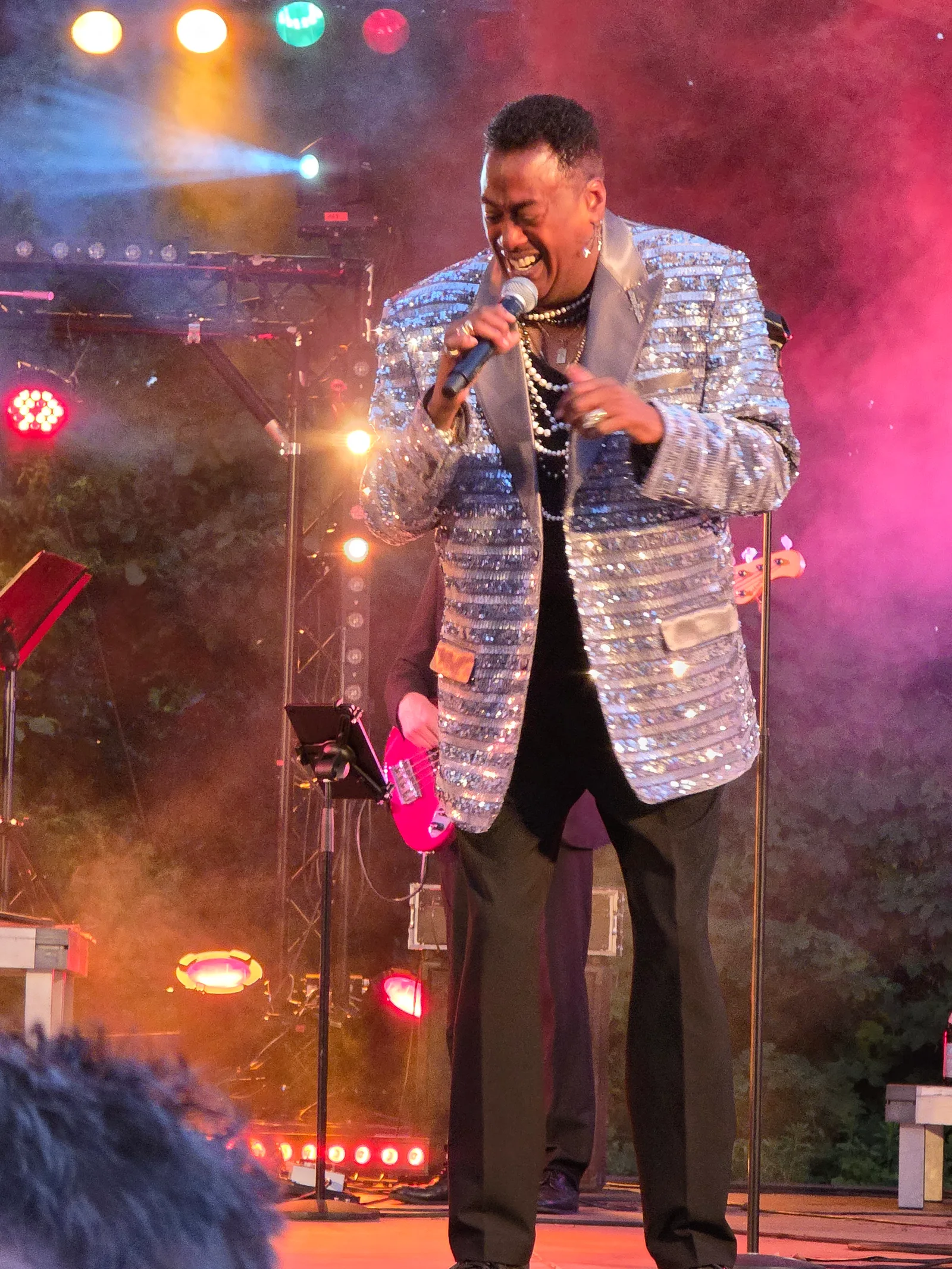 Keith singt im silbernen Sakko im farbigen Bühnenlicht